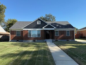 A two-story house with a brick facade, a dark roof, and a front porch. - Midtown Historic 3BR - Quiet + Workspace (Memphis)