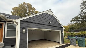 Un garage à l’extérieur sombre, avec une porte blanche et une allée en béton.