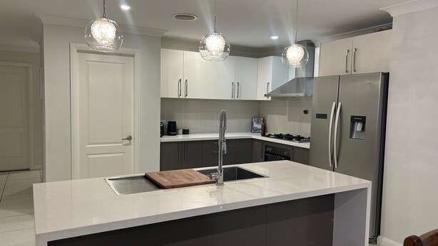 A modern kitchen with white cabinetry, a stainless steel refrigerator, and pendant lighting. - Lap of Luxury- Bathurst House
Very generous floor plan with dual living areas (Kelso)