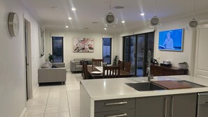 A modern kitchen with a central island, dining area with chairs, a sofa, and a TV mounted on the wall. - Lap of Luxury- Bathurst House
Very generous floor plan with dual living areas (Kelso)
