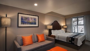 A hotel room with a grey sofa, a bed with a white comforter, a framed painting on the wall, and a window with curtains. - 2 Bedroom - Marriott's Mountainside ski in ski out resort at Park City, UT (Park City)