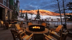 An outdoor seating area with a fire pit surrounded by wooden chairs, overlooking a snowy landscape with a mountain in the background. - 2 Bedroom - Marriott's Mountainside ski in ski out resort at Park City, UT (Park City)