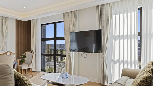 A modern living room with a large TV, comfortable seating, and a view of the outdoors. - Lake Haven apartment 1 - wonderful location near lake and town (Taupō)