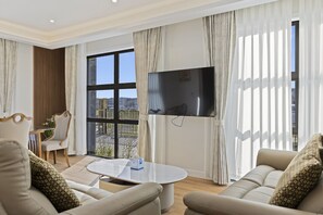 A modern living room with a large TV, comfortable seating, and a view of the outdoors.