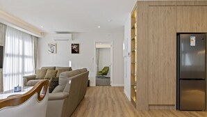 A modern living room with a sofa, a dining table, and a built-in wooden cabinet. - Lake Haven apartment 1 - wonderful location near lake and town (Taupō)