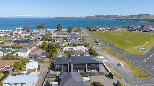 An aerial view of a residential area with houses, a road, and a body of water in the background.