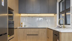 A modern kitchen with wooden cabinets, a marble backsplash, and a stainless steel refrigerator. - Lake Haven apartment 1 - wonderful location near lake and town (Taupō)