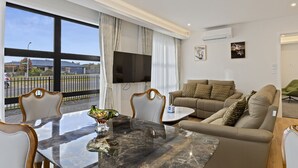 A modern living room with a marble table, a beige sofa, and a large window offering a view of the outside. - Lake Haven apartment 1 - wonderful location near lake and town (Taupō)