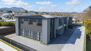A modern building with a flat roof, large windows, and a paved entrance area. - Lake Haven apartment 1 - wonderful location near lake and town (Taupō)