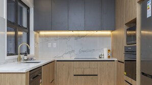 A modern kitchen with marble countertops, wooden cabinets, and under-cabinet lighting.