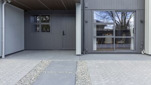 A modern building with a grey exterior, a large sliding glass door, and a small window.