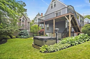 Ein Haus mit überdachter Veranda, Whirlpool und gepflegtem Rasen.