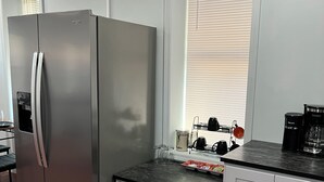 Eine moderne Küche mit einem Edelstahl-Kühlschrank, weißen Schränken und einer schwarzen Arbeitsplatte.