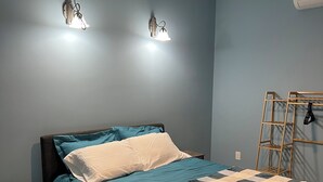 Ein Schlafzimmer mit einem Bett, zwei Wandleuchten, einer Holzleiter und einem gemusterten Teppich.