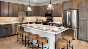 Una cocina moderna con armarios de madera, electrodomésticos de acero inoxidable y una isla central con taburetes.