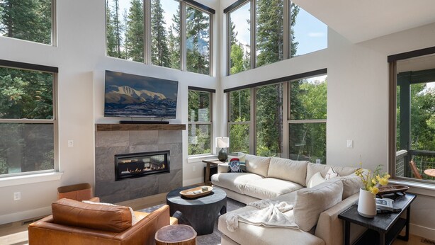 Una sala de estar moderna con chimenea, ventanas amplias y un sofá.