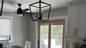 Eine moderne Küche mit weißen Schränken, einer Marmorarbeitsplatte und einem Deckenventilator.