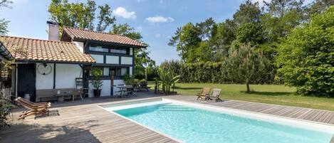 A modern house with a swimming pool, wooden deck, and outdoor furniture.