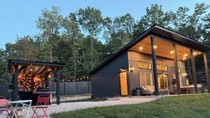 Une cabane moderne dotée d’un patio, d’un espace salon extérieur et d’un barbecue.