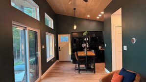 Une cuisine moderne avec des meubles de couleur sombre, un plafond en bois et un coin repas comprenant une table et des chaises.