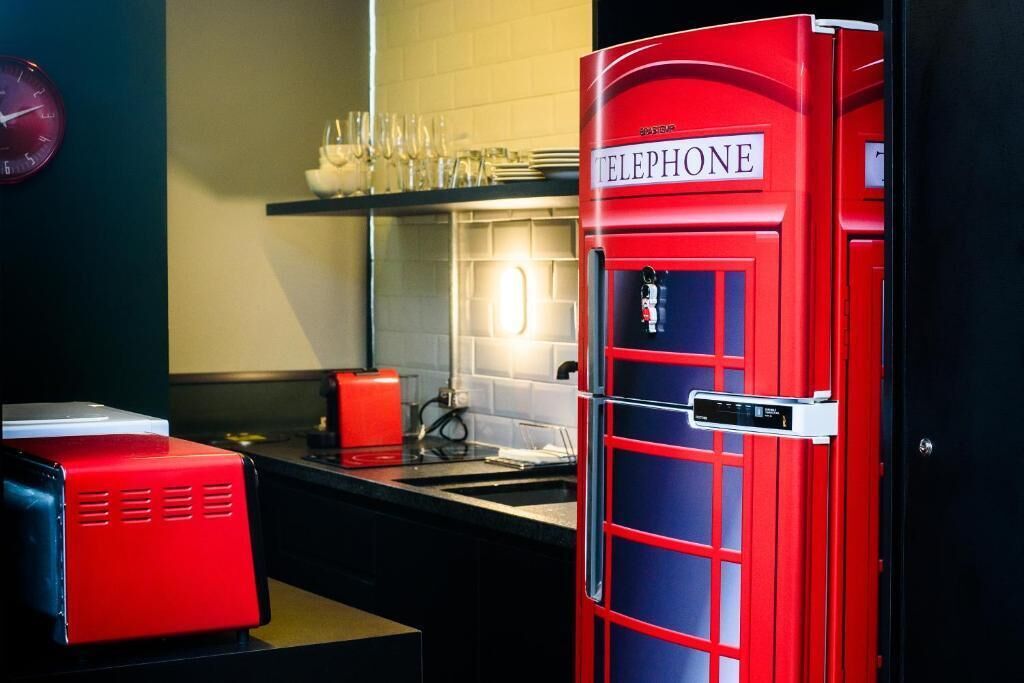 A red telephone booth in a modern kitchen with a sink and countertop appliances.