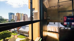 A hotel room with a city view, a bed, a TV, and a balcony. - LUIX LONDRINA FLAT (Londrina)
