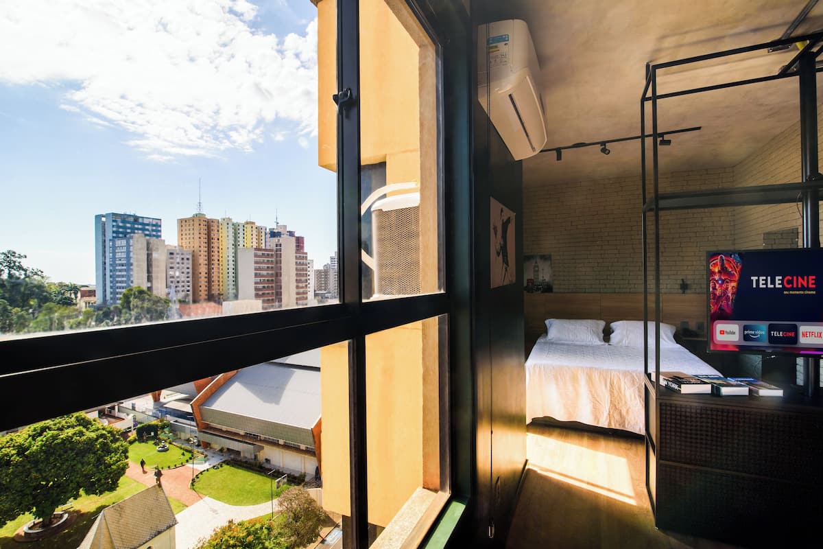 A hotel room with a city view, a bed, a TV, and a balcony.