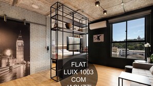 A modern room with a large window, a bed, a sofa, and a unique black shelving unit. - LUIX LONDRINA FLAT (Londrina)