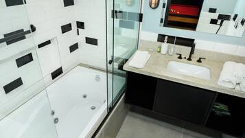 A modern bathroom with a glass-enclosed bathtub, a vanity with a sink, and a mirror above the mirror cabinet.