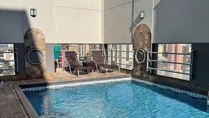 A rooftop pool with a clear view of the cityscape, stone archways, and lounge chairs. - LUIX LONDRINA FLAT (Londrina)
