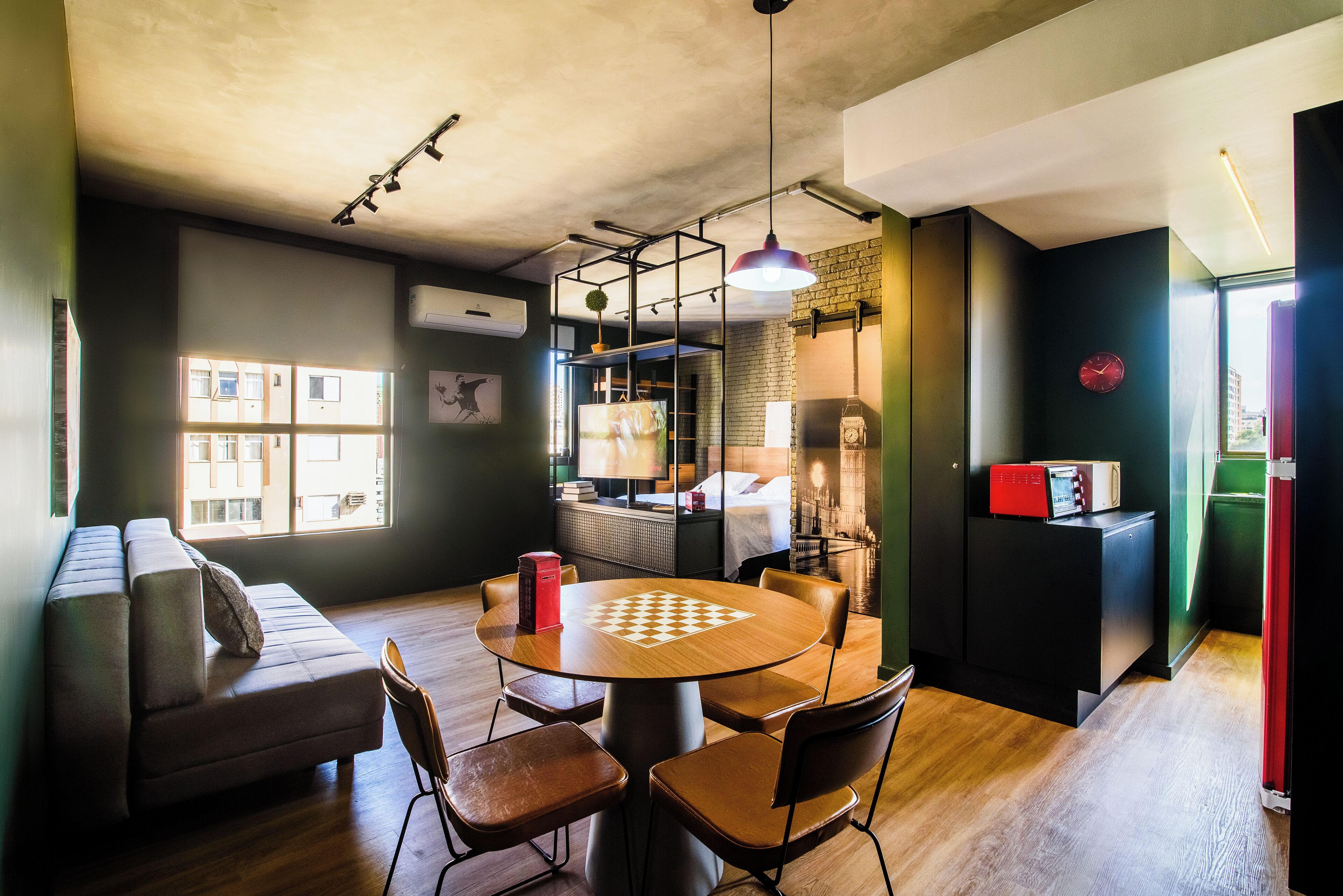 Una habitación acogedora con piso de madera, una mesa redonda con sillas, un sofá y una cama con cabecera.