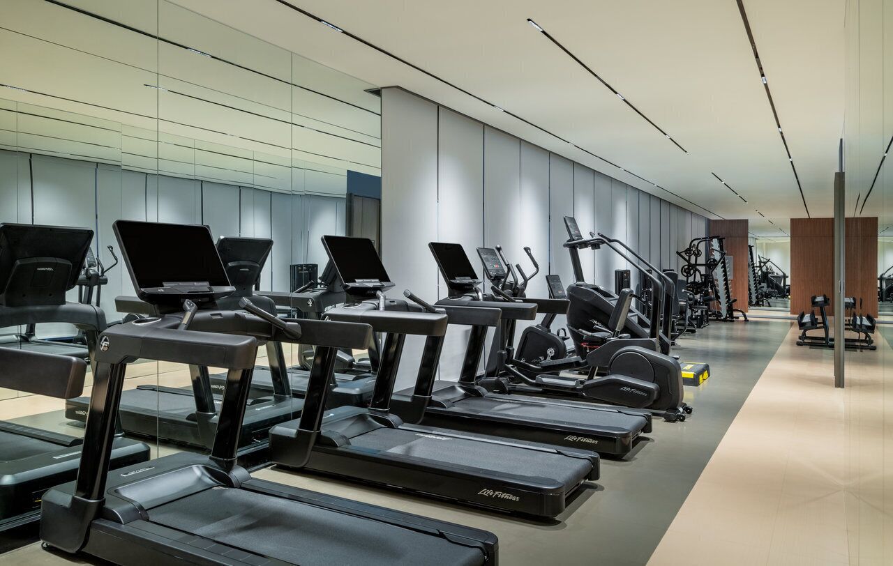 Ein modernes Fitnessstudio mit mehreren Laufbändern, Ergometer und Krafttrainingsgeräten.