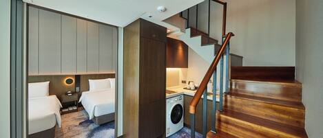 Habitación de hotel pequeña con cama, lavadora y una escalera.