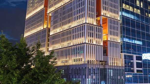 A modern high-rise building with a grid-like facade and illuminated windows at night. - HOTEL HLB (Busan)