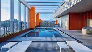 A rooftop pool with lounge chairs, a stone wall, and a view of the city. - HOTEL HLB (Busan)