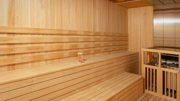 A wooden sauna with benches and a small hourglass on the floor.