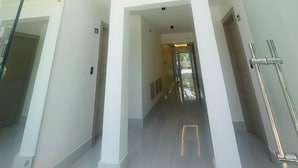 A modern interior with a glass balustrade, a central column, and a hallway leading to a door.