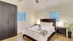 Ein Schlafzimmer mit einem hölzernen Bett, zwei Nachttischen, einem Beistelltisch und einem Fenster.