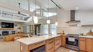 Eine moderne Küche mit einer großen Kochinsel, Holzschränken und einem eingebauten Backofen.