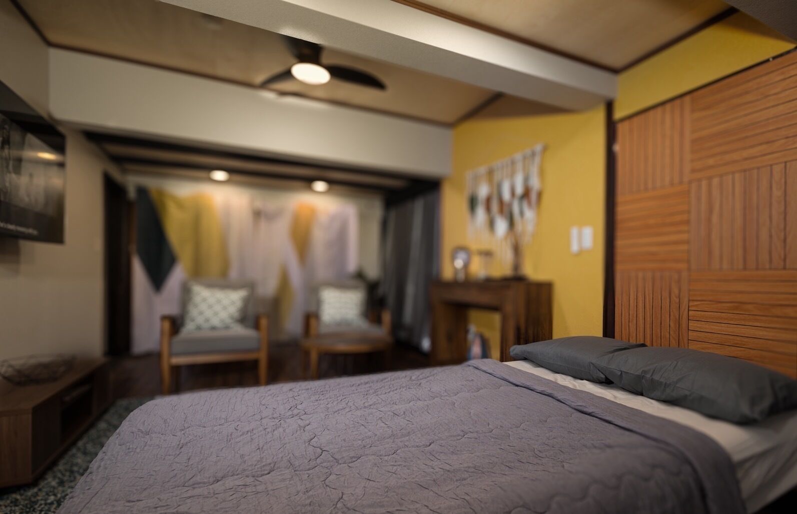 A bedroom with a bed, a wooden wardrobe, and a chair.
