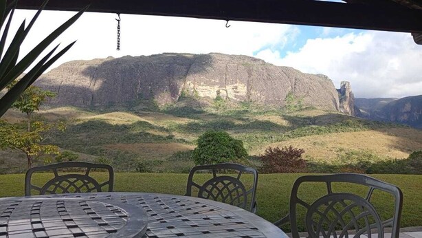 An outdoor seating area with a table and chairs, overlooking a mountainous landscape.