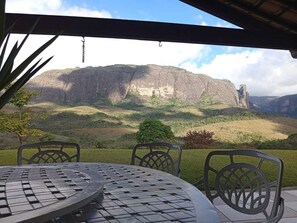 Ein Sitzbereich im Freien mit Tisch und Stühlen mit Blick auf eine Berglandschaft.