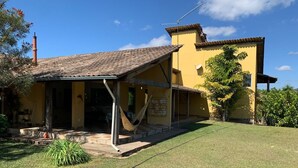 A yellow building with a tiled roof, a covered porch, and a hammock.