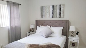 A neatly arranged bedroom with a large bed, two bedside tables, a wall-mounted artwork, and a fur throw on the bed. - Dania Beach 1BR Retreat - Private Entry & Self Check-In (Dania Beach)