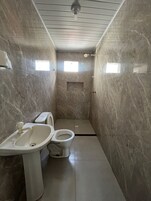A small, compact bathroom with a toilet, sink, and shower.