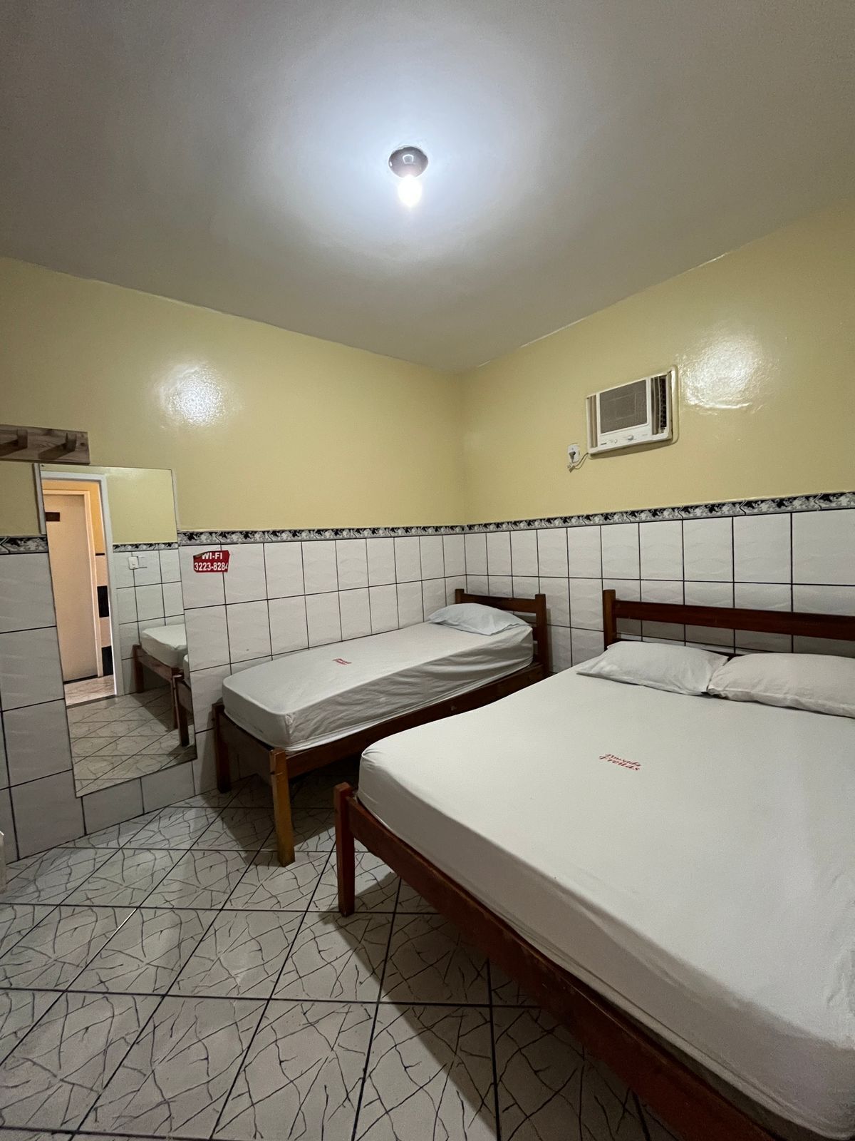 Une petite chambre propre, avec deux lits simples, des toilettes et un lavabo.