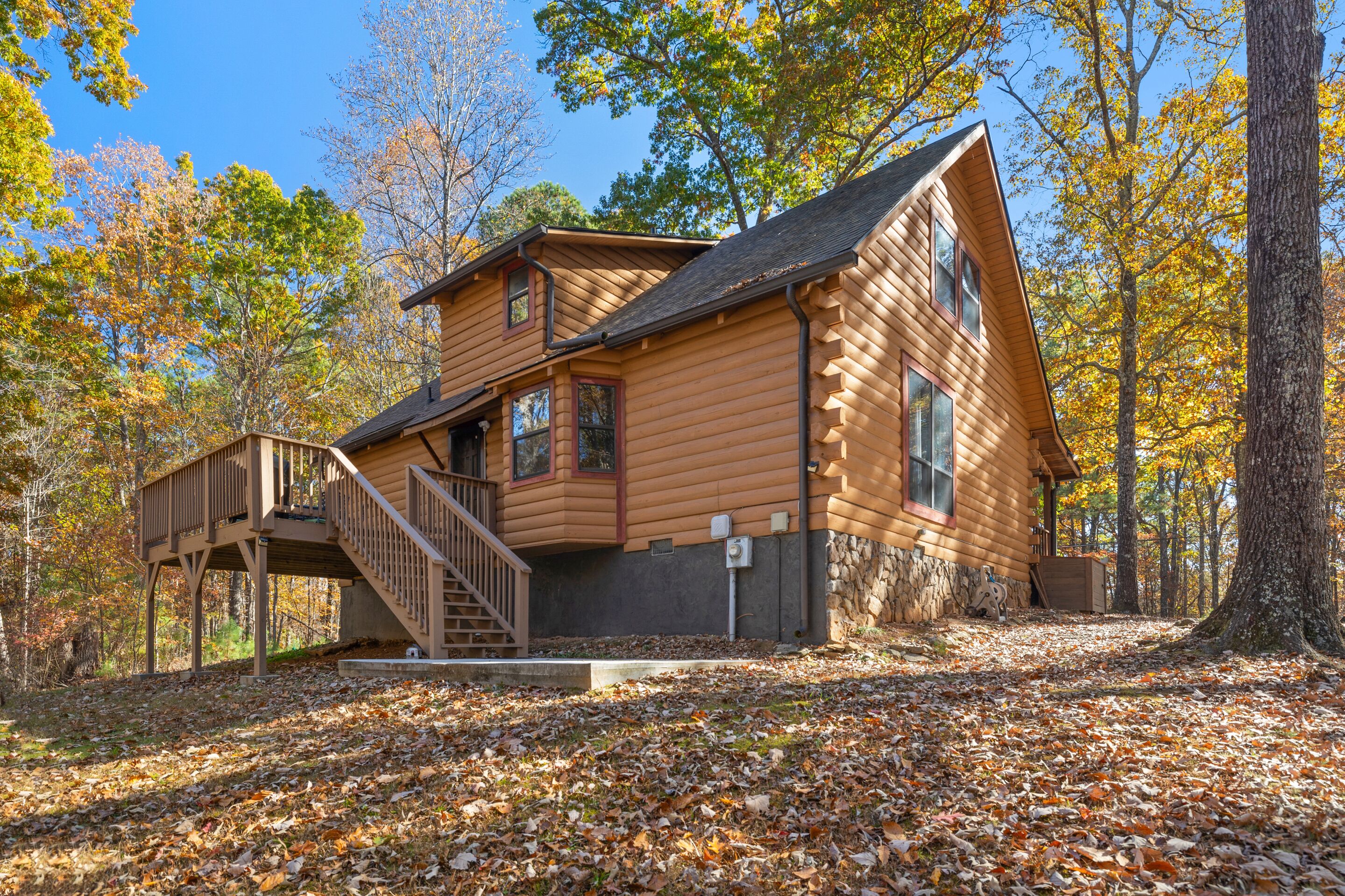 A log cabin with a wooden deck and a staircase leading to the entrance.