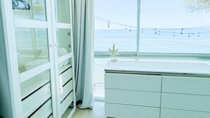 Une pièce dotée d’une grande fenêtre, d’une armoire blanche et offrant une vue sur la mer.