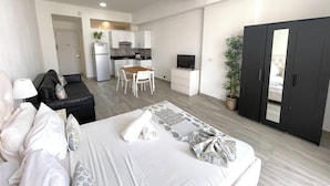 Ett modernt hotellrum med en säng, ett litet pentry, en matplats och en garderob.