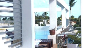 En balkong med utsikt över en swimmingpool, ett trädäck och en krukväxt.
